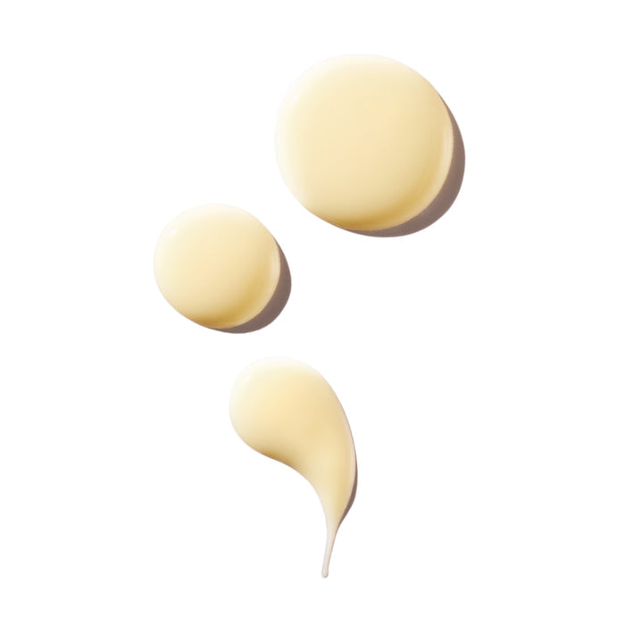 Three drops of Ursa Majors Lunar Bloom Retinal Serum, a creamy light yellow formula, are arranged on a white background, showcasing its smooth texture for improving skin texture and targeting fine lines.