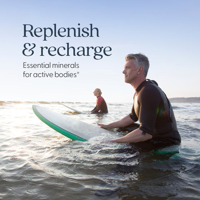 Two people sit on surfboards in the ocean at sunset. Text reads: Replenish & recharge with New Chapter Magnesium-Selenium-Zinc Supplement—essential minerals for active bodies.*.