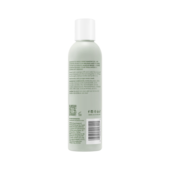 A bottle of EcoTools Makeup Brush & Sponge Shampoo with a white cap features a label with green and black text highlighting its paraben-free formula and usage instructions. The back shows contact information, social media icons, and a barcode.