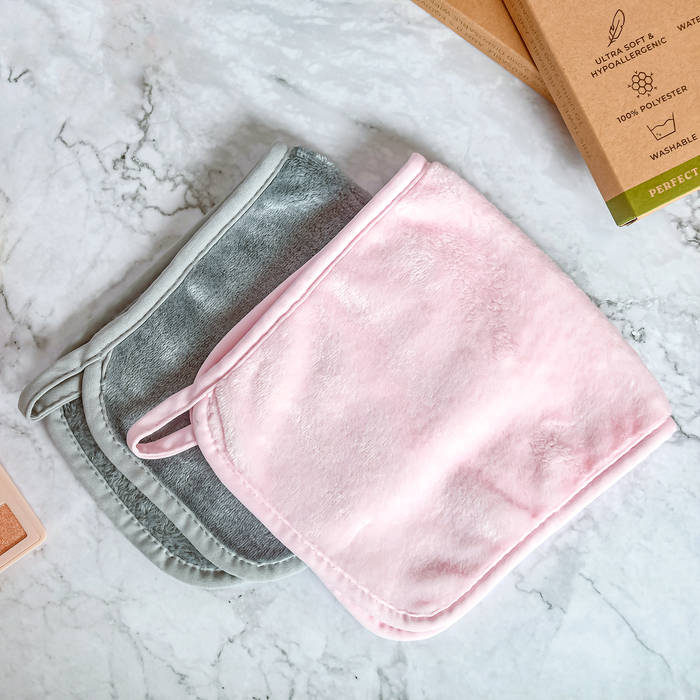 Two Makeup Remover Towels from Tree To Tub, one gray and smooth, the other pink and fluffy for a gentle cleanse, rest neatly on marble. Nearby, cardboard packaging is partially visible—ideal as reusable essentials.