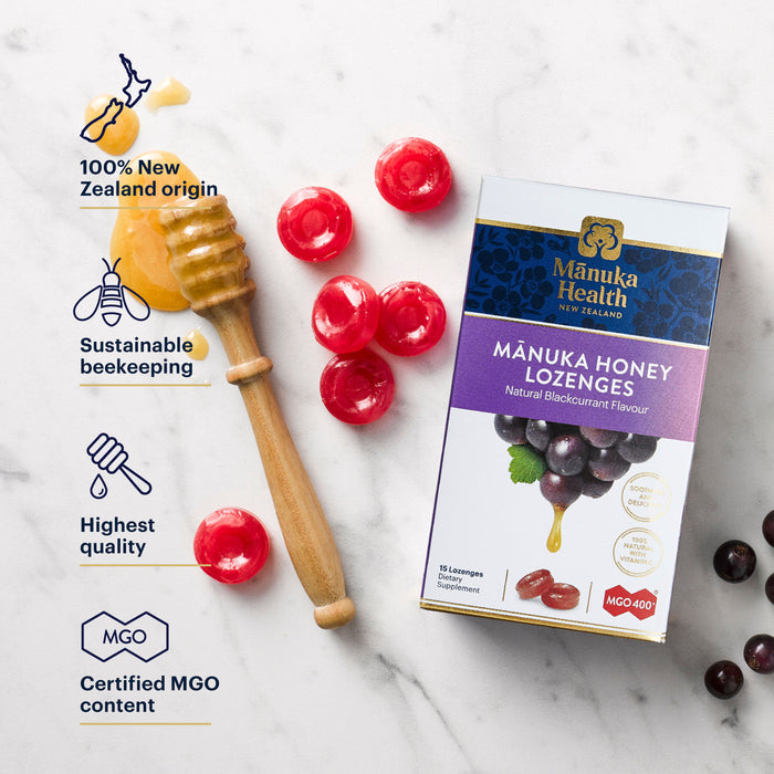 A box of Mānuka Health lozenges with natural blackcurrant flavor is displayed on a marble surface. Red lozenges and honey on a dipper are nearby. Icons highlight features like New Zealand origin, sustainable beekeeping, and certified MGO content.