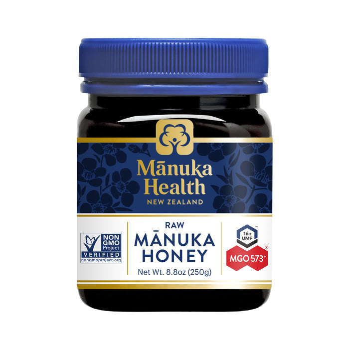 The 8.8 oz jar of Manuka Healths raw Manuka Honey features a blue lid and boasts UMF 16+ and MGO 573+ ratings. Its Non-GMO verified, catering to honey enthusiasts seeking premium quality.
