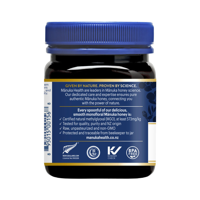 A jar of Manuka Healths UMF 16+ Manuka Honey displays a blue label accentuating its natural, non-GMO, certified attributes. It highlights an MGO 573+ content and includes various certifications plus a website URL, with the labels colors mainly being blue, white, and gold.