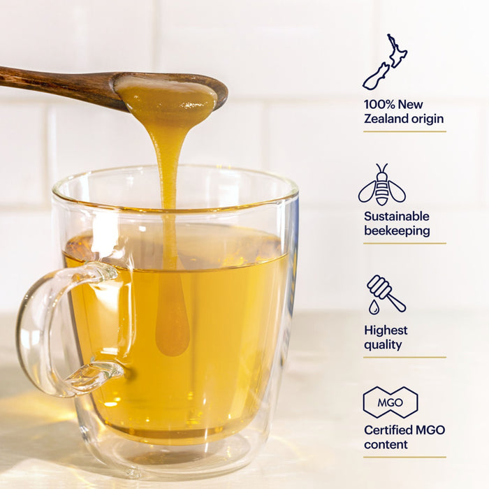 A spoon drizzles honey into a clear mug of tea. Text next to the mug reads: "100% New Zealand origin," "Sustainable beekeeping," "Highest quality," and "Certified MGO content," with related icons.