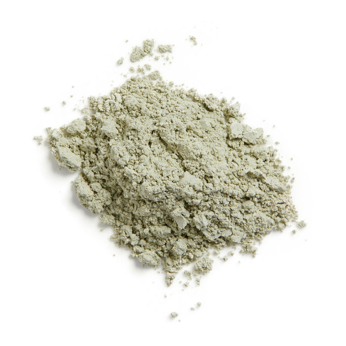 A pile of light gray powder, with a coarse, uneven texture, is scattered on a white surface. Resembling Terra Beauty Bars Matcha Sea Dry Facial Clay Masks antioxidant-rich formula, it features small clumps and loose particles that enhance its unique character.
