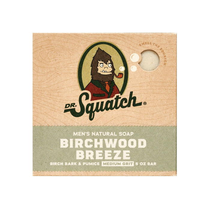 Packaging for Dr. Squatch Mens Bar Soap, Birchwood Breeze scent, features a suit-clad Sasquatch mascot, hinting at adventure like Coconut Castaway. Medium grit 5 oz bar with birch bark and pumice. Brown and green design.