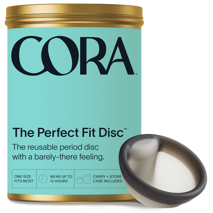 A light turquoise container labeled Cora: The Perfect Fit Disc presents the reusable Cora Menstrual Disc featuring a black rim and white center, offering versatile sizing, up to 12 hours of leak-free protection, and comes with a convenient carry case.