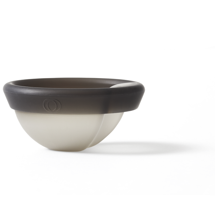 A modern, round bowl on a white background mimics the two-toned look of a Cora Menstrual Disc, with a dark rim and lighter base. Its sleek design includes an embossed circular logo, symbolizing leak-free protection.
