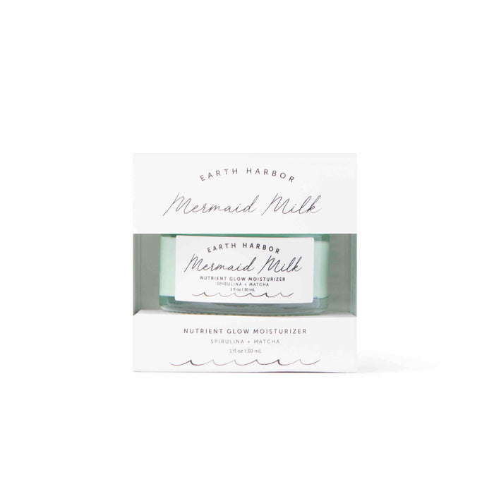 A MERMAID MILK jar by Earth Harbor emerges from a white box, highlighting the superfoods spirulina and matcha. This vegan moisturizer combines nutrients with hyaluronic acid for glowing skin.