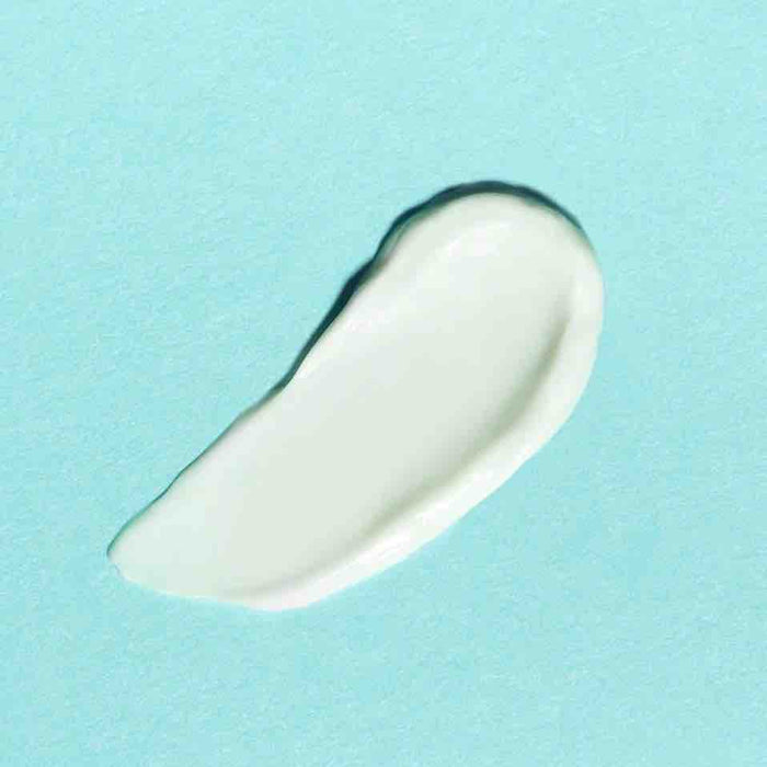 A smooth, curved smear of Earth Harbors MERMAID MILK Nutrient Glow Moisturizer, infused with Vegan Hyaluronic Acid, graces a pastel blue background.
