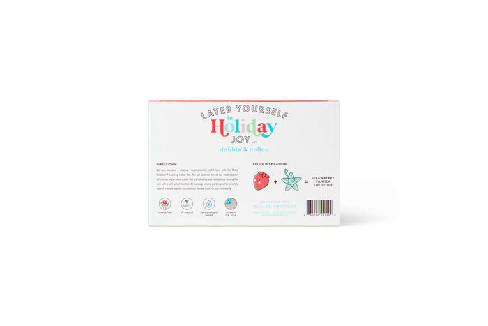 The back of the Merry Mixables Layering Lotions gift set by Dabble & Dollop showcases Layer Yourself Holiday Joy in colorful letters. It includes recipe ingredients, directions, and charming illustrations of a strawberry and smoothie cup in festive red, green, and white tones for your custom-scented creation.