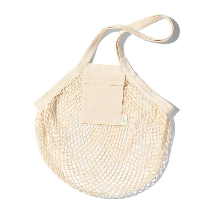 The Grove Co. Mesh Farmers Market Tote is a cream-colored, round, netted bag made from organic cotton, featuring a solid fabric top and single long handle. A minimalist design with a small front pocket on a white background—an epitome of stylish sustainability.