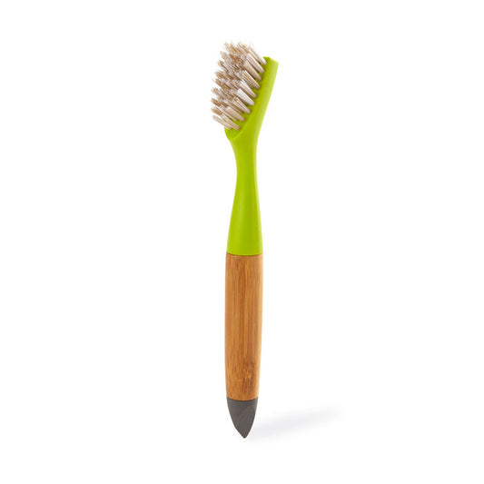 The Full Circle Micro Manager Detail Brush, featuring white bristles, a green plastic neck, a wooden handle, and a dark pointed tip, stands upright on a white background—ideal for precise kitchen cleaning.