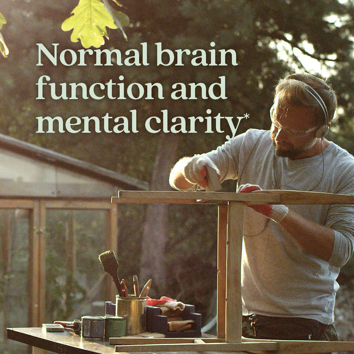 A man in headphones uses a power tool on a wooden project outdoors. Sunlight streams through the trees. Text: Mind Force™, Lion’s Mane Mushroom Blend for Mental Clarity by New Chapter—supports normal brain function.*.