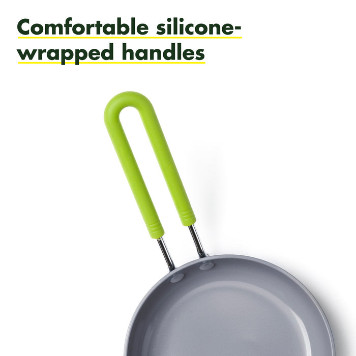Top view of a grey frying pan with vibrant green silicone-wrapped handles. Text in the top left corner reads "Comfortable silicone-wrapped handles" in bold green letters. The minimalistic design emphasizes the pan's functionality and comfort.
