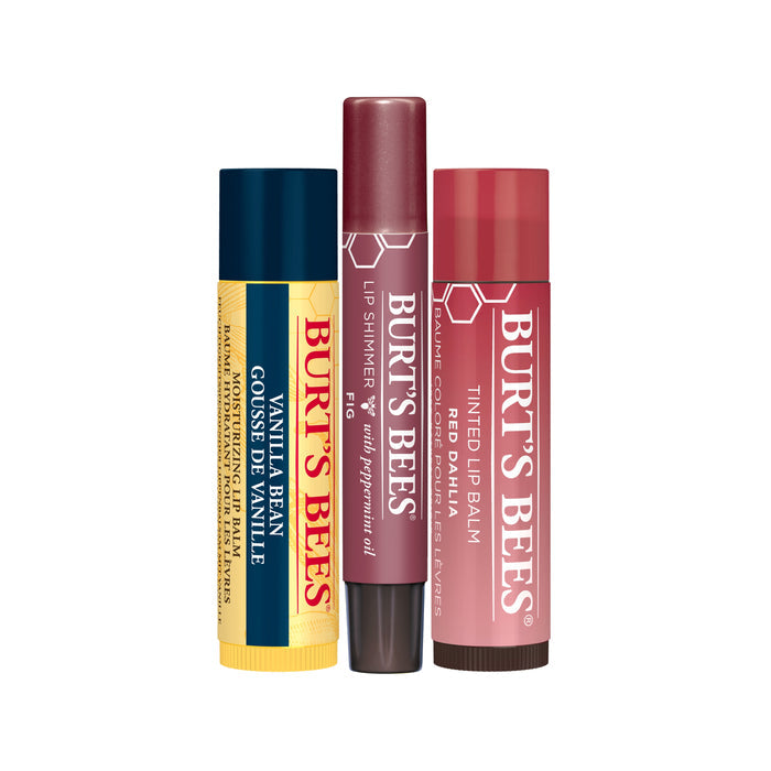 The Mistletoe Kiss Gift by Burts Bees features three elegantly arranged lip products: a yellow tube of Vanilla Bean Lip Balm, a maroon Lip Shimmer with peppermint oil, and a pinkish-red Tinted Lip Balm, each providing unique nourishment.