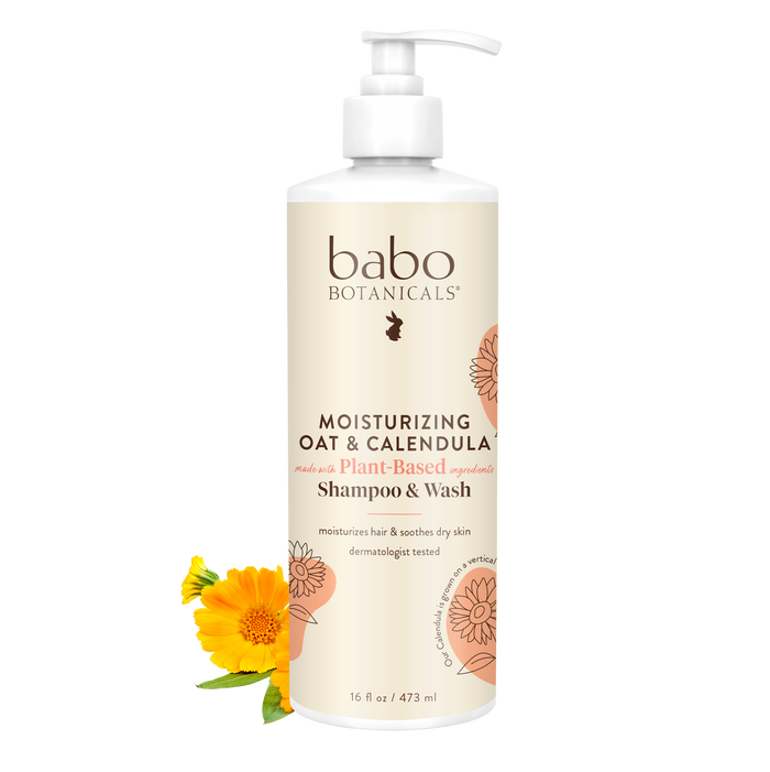 A 16 fl oz bottle of Babo Botanicals Moisturizing Shampoo & Wash features a pump dispenser and a floral label highlighting its plant-based cleansers, with a calendula flower beside the bottle.
