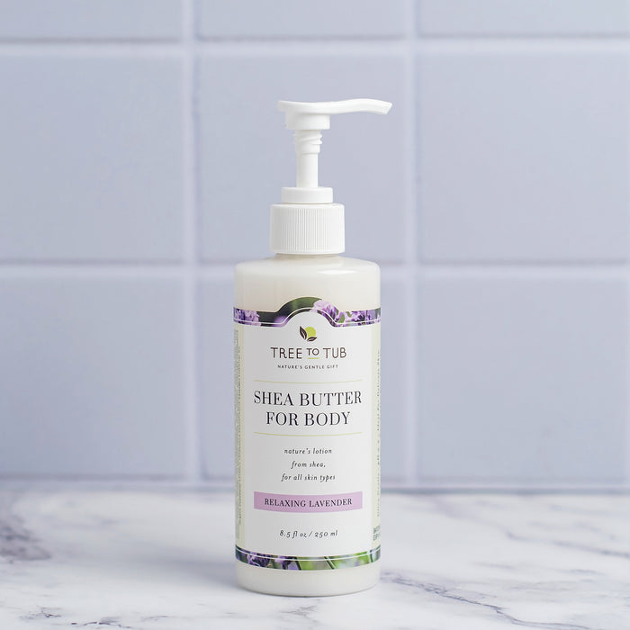 A bottle of Tree To Tub Moisturizing Shea & Cocoa Butter Lotion for Dry Skin with a pump dispenser sits on a marble surface. The label highlights its relaxing lavender scent suitable for all skin types, set against light blue tiles, ideal for those seeking a hydrating lotion experience.