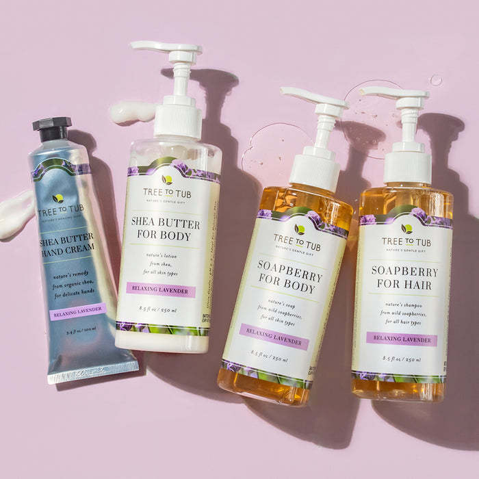 Four Tree To Tub products, including a tube of shea butter hand cream and three pump bottles labeled Shea Butter for Body, Soapberry for Body, and Soapberry for Hair, rest on a pink background. All have the Relaxing Lavender scent, perfect as a Moisturizing Shea & Cocoa Butter Lotion for Dry Skin.