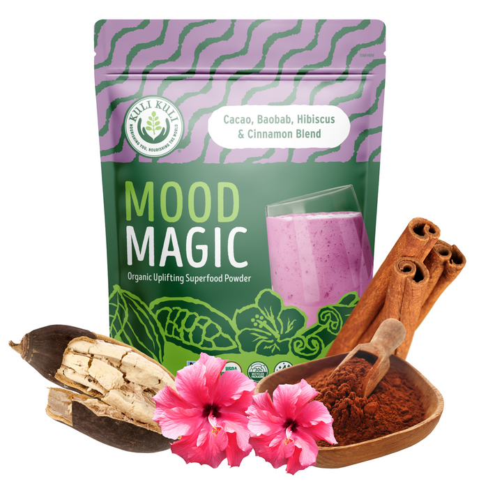 A pouch of Kuli Kuli Foods Mood Magic Organic Superfood Blend, containing cacao, baobab, hibiscus, and cinnamon, features a purple wave with green accents and a smoothie image. Cinnamon sticks, powder scoop, vivid hibiscus flowers, and exotic baobab fruit surround the pouch.