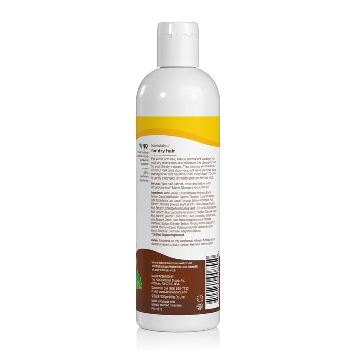A white plastic bottle of Alba Botanica More Moisture Coconut Milk Shampoo with a yellow and brown label is shown from the back, displaying product info, directions, ingredients, and a barcode. This sulfate-free shampoo is for dry hair.
