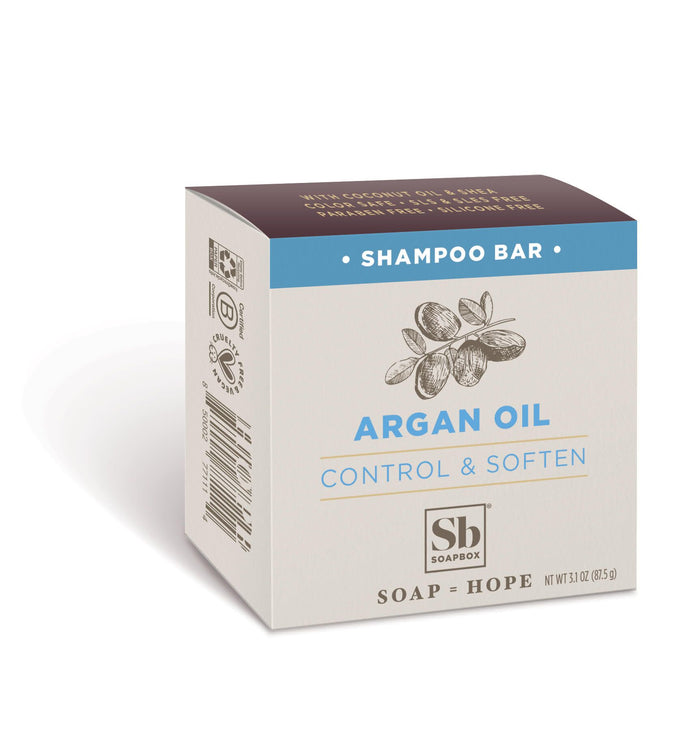 A beige and blue box of Soapboxs Moroccan Argan Oil Shampoo Bar features argan nut illustrations, emphasizes Control & Soften, and weighs 3 oz (85 g). Enjoy argan oil benefits while aiding plastic waste reduction.