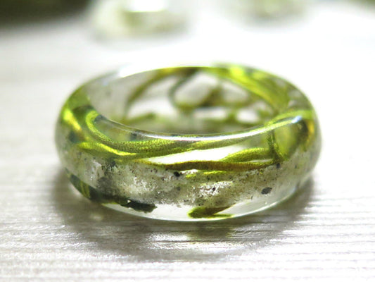 Close up of a green moss ring encased in clear resin containing cremains.