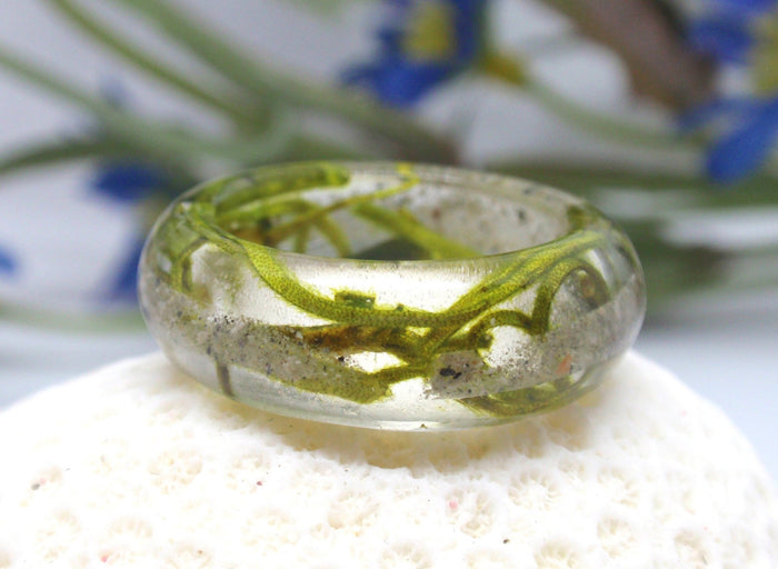 Side view of moss ring set in clear resin with visible cremains and moss.