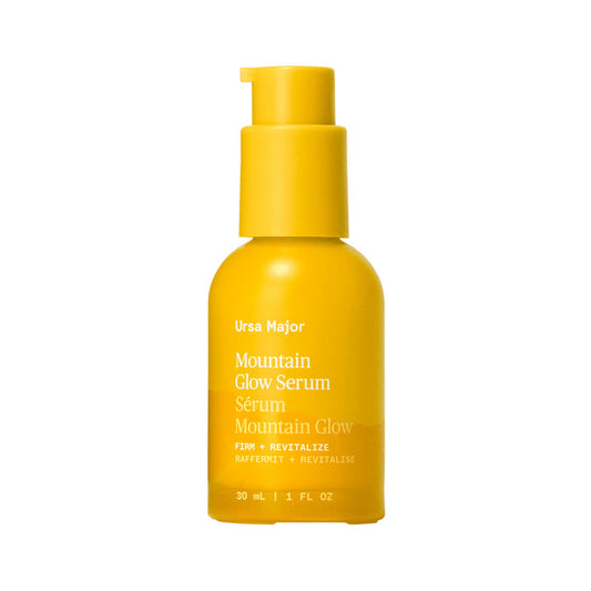 A 30 mL (1 fl oz) yellow bottle of Ursa Major Mountain Glow Serum with pump dispenser, labeled Firm + Revitalize, offers rejuvenating skin nutrition.