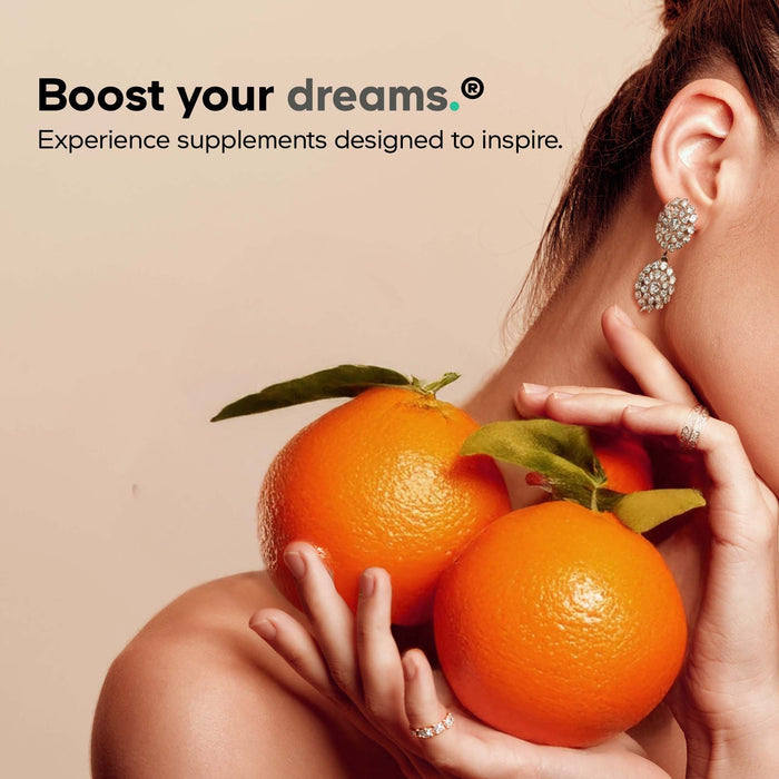 A woman holding two large oranges near her neck, wearing sparkling earrings and rings. Text above reads, Boost your dreams with Codeage Amen Vitamin D, K2 & Zinc—vegan supplements made to inspire and support immunity.