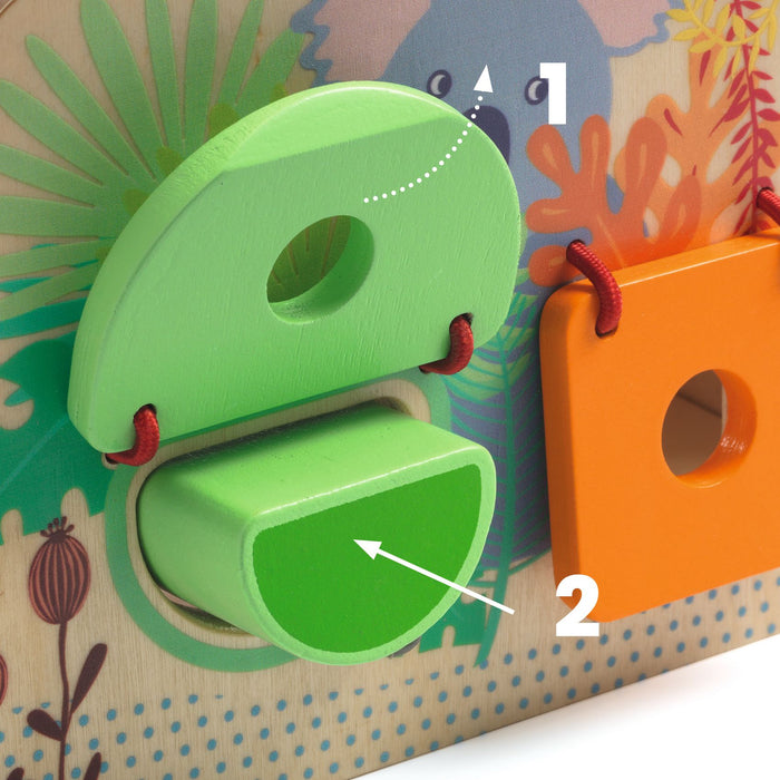 Close-up of a colorful wooden toy with numbered steps for guiding shapes through matching holes. A green semicircular piece fits into a matching green hole, and an orange square piece hangs next to it. Background shows playful illustrations.