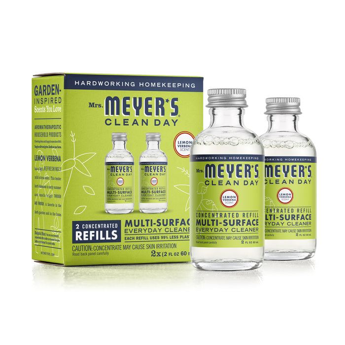 Box with two bottles of Mrs. Meyers Multi-Surface Concentrate Refills in Lemon Verbena scent, featuring garden-inspired packaging and a caution for capsule pressure.