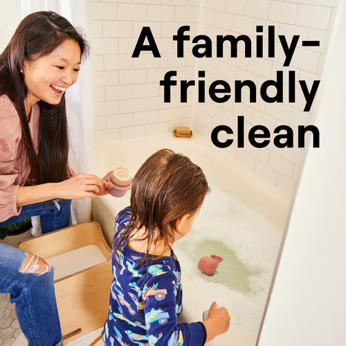 An adult and child enjoy playtime in a bubbly bathtub. Large text reads, A family-friendly clean with Seventh Generation Multi-Surface Disinfectant Cleaning Spray, helping protect against household germs. The bright bathroom feels cheerful and welcoming.