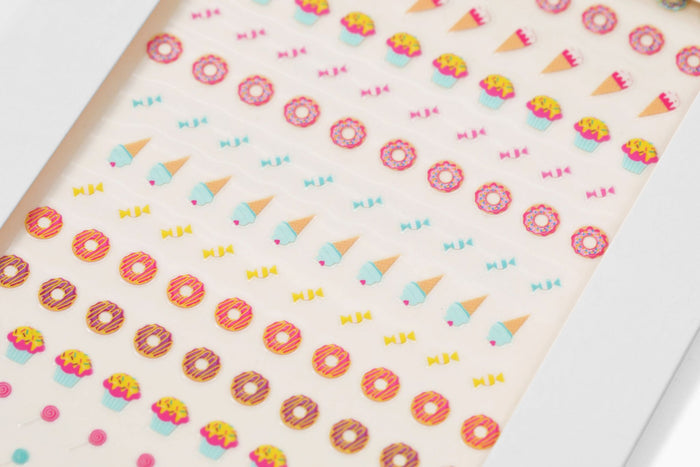 Vibrant Nail Art Stickers by Terra Beauty Bars feature rows of cupcakes, ice cream cones, donuts, and bows on a white background—ideal for nail art enthusiasts seeking stylish, sustainable nail care.