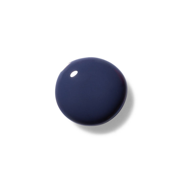 A shiny round blob of Terra Beauty Bars vegan Nail Polish in dark blue sits against a white background, reflecting light.