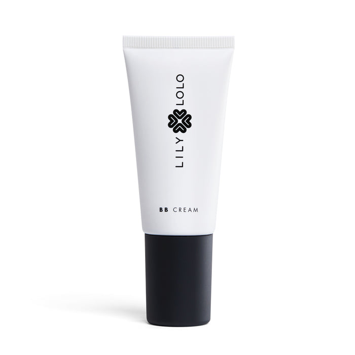 A white tube of Lily Lolos Natural BB Cream with a black cap features a minimalist design with the brands name in vertical black letters. This silicone-free Beauty Balm, enhanced with mineral pigments, ensures a flawless finish.