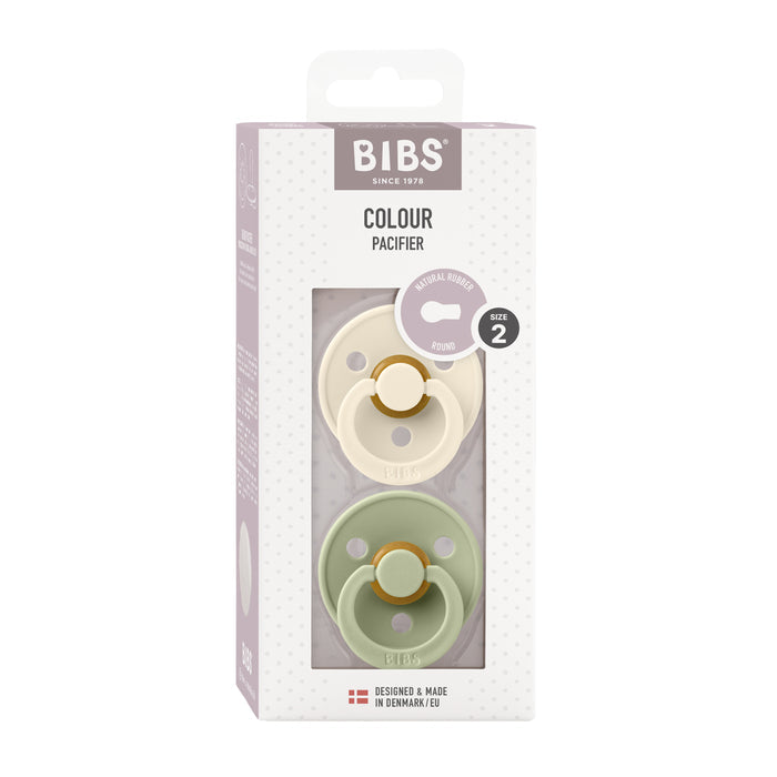 The BIBS Natural Latex Rubber Pacifier, Size 2 (6-18 Months), features two pastel pacifiers in off-white and light green. Made in Denmark with BPA-free natural rubber, these round nipple pacifiers provide excellent breastfeeding support.