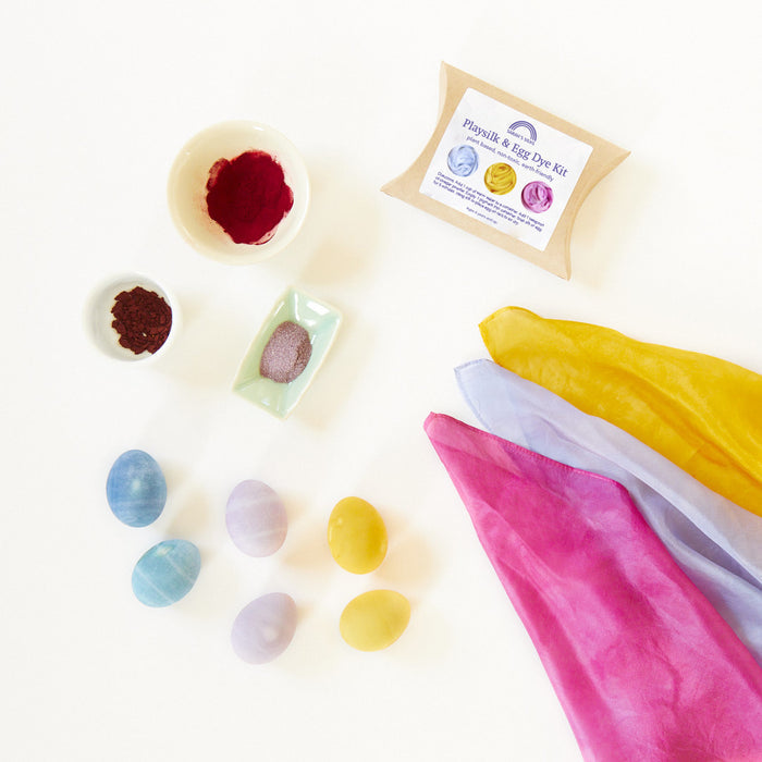 The Natural, Non-Toxic Easter Egg + Playsilk Dye Kit by Sarahs Silks includes a cloth, colorfully dyed eggs, small bowls of non-toxic dye powder, and packaging labeled with the product name. Its ideal for creating vibrant and safe designs on a white surface.
