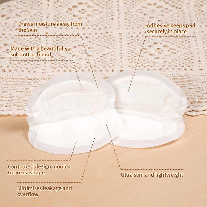 A pair of white breast pads on a wooden surface, near a crochet fabric. Text highlights features: moisture-wicking, secure adhesive, soft cotton blend, contoured design, ultra slim, minimizes leakage.