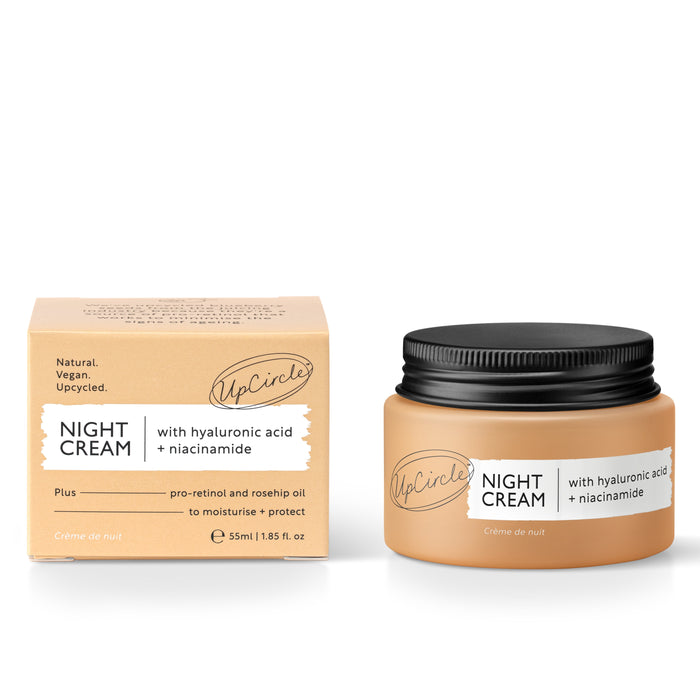 The UpCircle Night Cream with Hyaluronic Acid, Blueberry Extract, and Niacinamide sits beside its tan box adorned with black text highlighting its vegan and upcycled attributes. The jar holds 55ml (1.85 fl. oz) of nourishing cream.