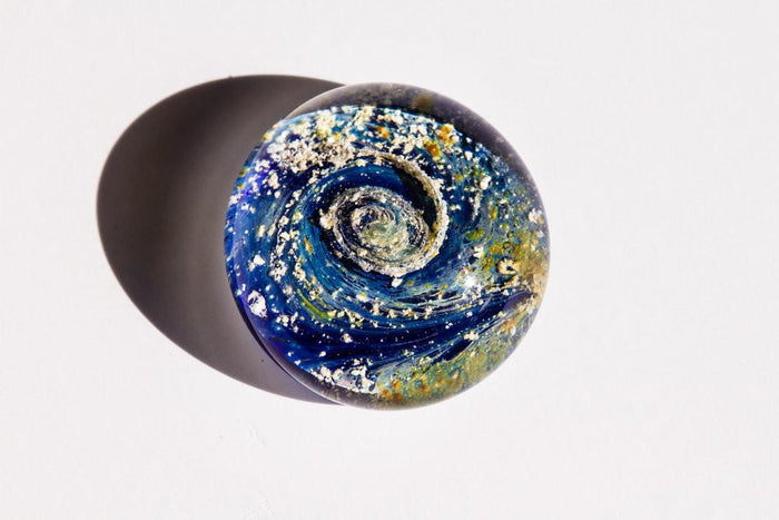 Top-down view of a blue galaxy worry stone infused with cremation ashes.