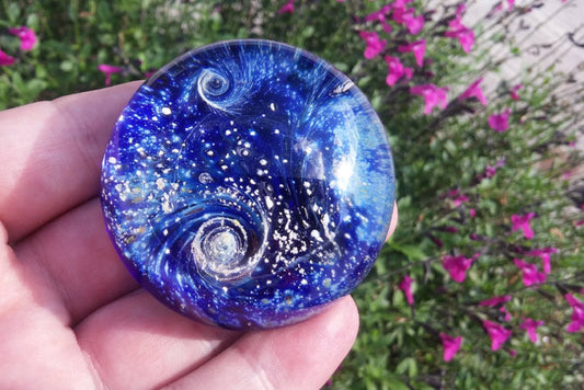 Blue Nightswirl glass paperweight with a space scene and a comet infused with cremation ash