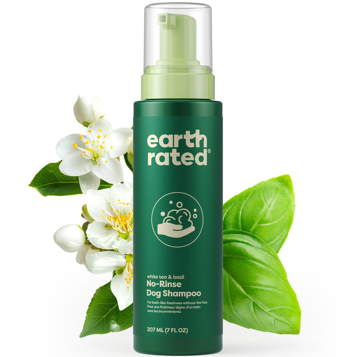 A green bottle of Earth Rateds hydrating No-Rinse Foaming Dog Shampoo, featuring a white tea and basil scent, surrounded by white flowers and green leaves. This deodorizing formula is conveniently available in a 207 ml (7 fl oz) size.