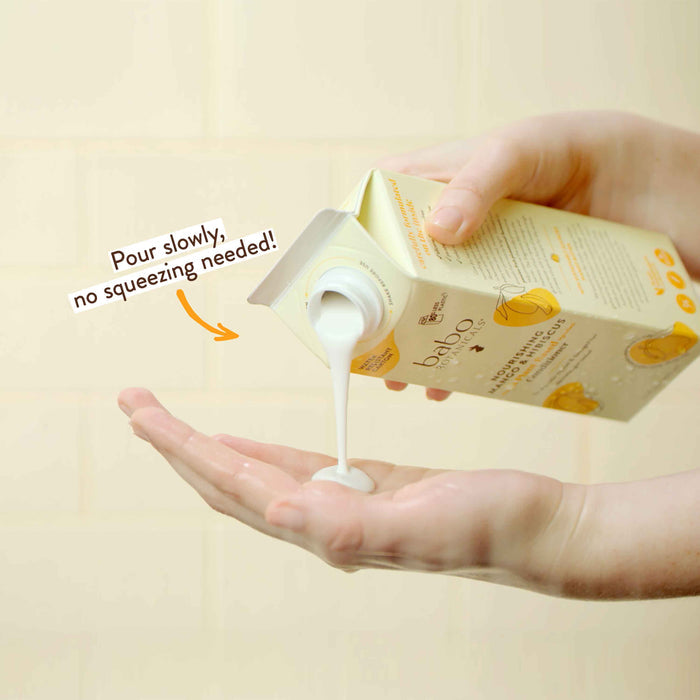 A person pours liquid soap onto their open palm from a carton labeled "baba" with a lemon illustration. Text on the carton reads, "Pour slowly, no squeezing needed!" The background is a soft, neutral color.