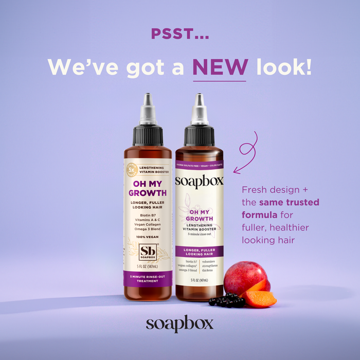 Two bottles of Soapbox Oh My Growth Lengthening Vitamin Booster Rinse-Out Treatment are shown against a purple background, offering fuller-looking hair. The packaging has a fresh design, with plum, peach, and berry at the base. It highlights a refreshed look while maintaining the same formula.