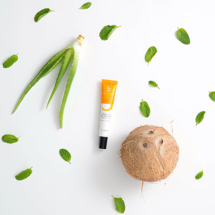 The Beauty by Earth Oil Control Facial Moisturizer, nestled among organic aloe vera leaves, mint, and a half coconut on white background, features natural ingredients for a refreshing addition to your beauty routine.
