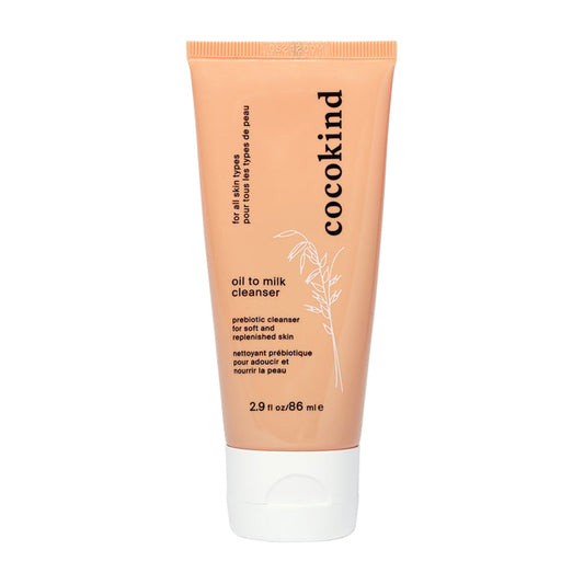 Image of a peach-colored Cocokind Oil to Milk Cleanser tube with black text detailing branding and product information, including probiotic cleanser and for soft and replenished skin. The organic formula features fermented oat oil blend. Tube size: 2.9 fl oz/86 ml.