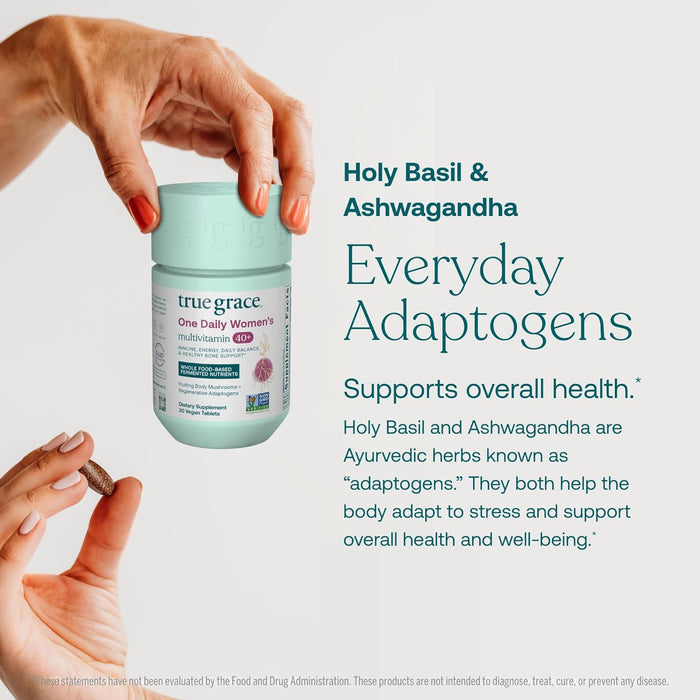 A hand holds a container of True Grace One Daily Women’s 40+ Multivitamin; another hand holds two capsules. Text beside reads: Holy Basil & Ashwagandha—everyday adaptogens with coenzyme B vitamins to support overall health.