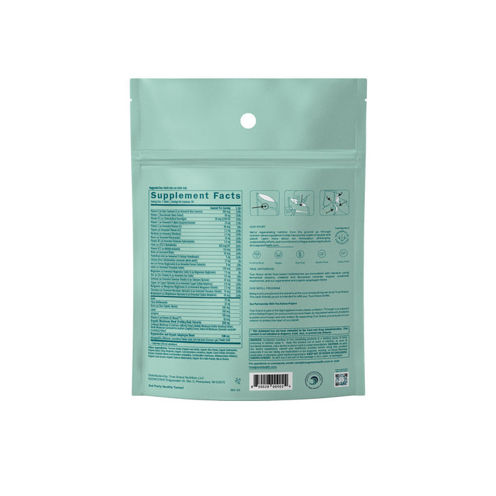 The image shows the back of a light green package for True Graces One Daily Womens Multivitamin Refill. A Supplement Facts label is featured, with instructions icons and contact info. Small text details include an organic mushroom blend, with a barcode at the bottom.