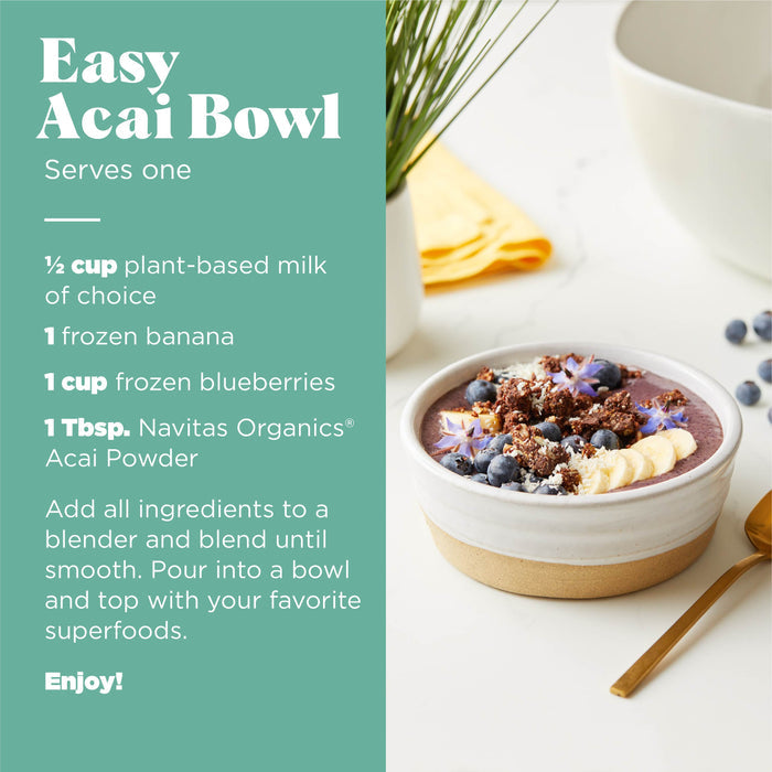 A vibrant acai bowl, packed with antioxidants, topped with beauty berries, bananas, blueberries, and granola, sits beside a green plant and yellow cloth. To the left is Navitas Organics Organic Acai Powder recipe for crafting this treat.